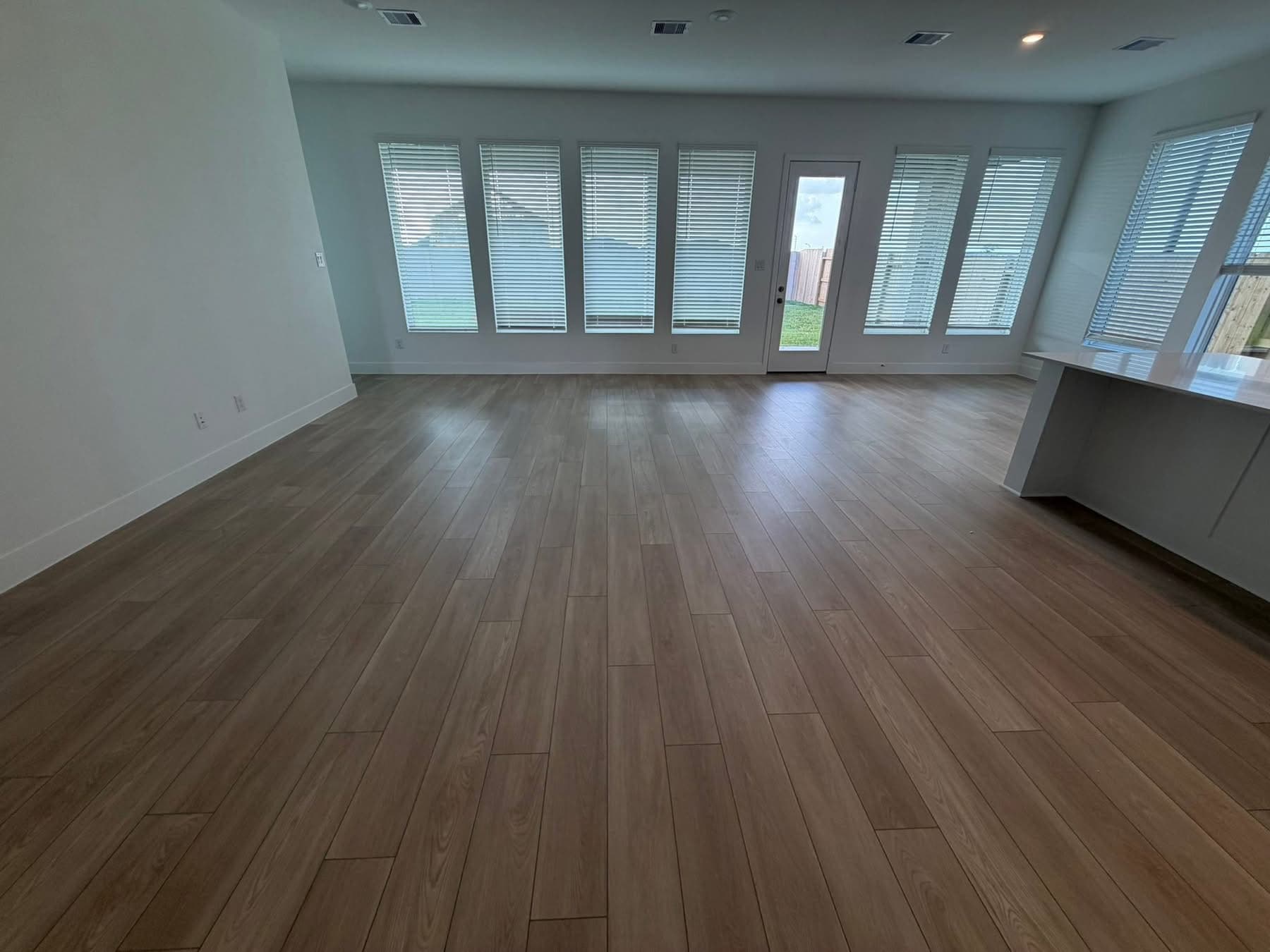 Light hardwood flooring installation in spacious living room with large windows โ 2M Construction Huntsville AL