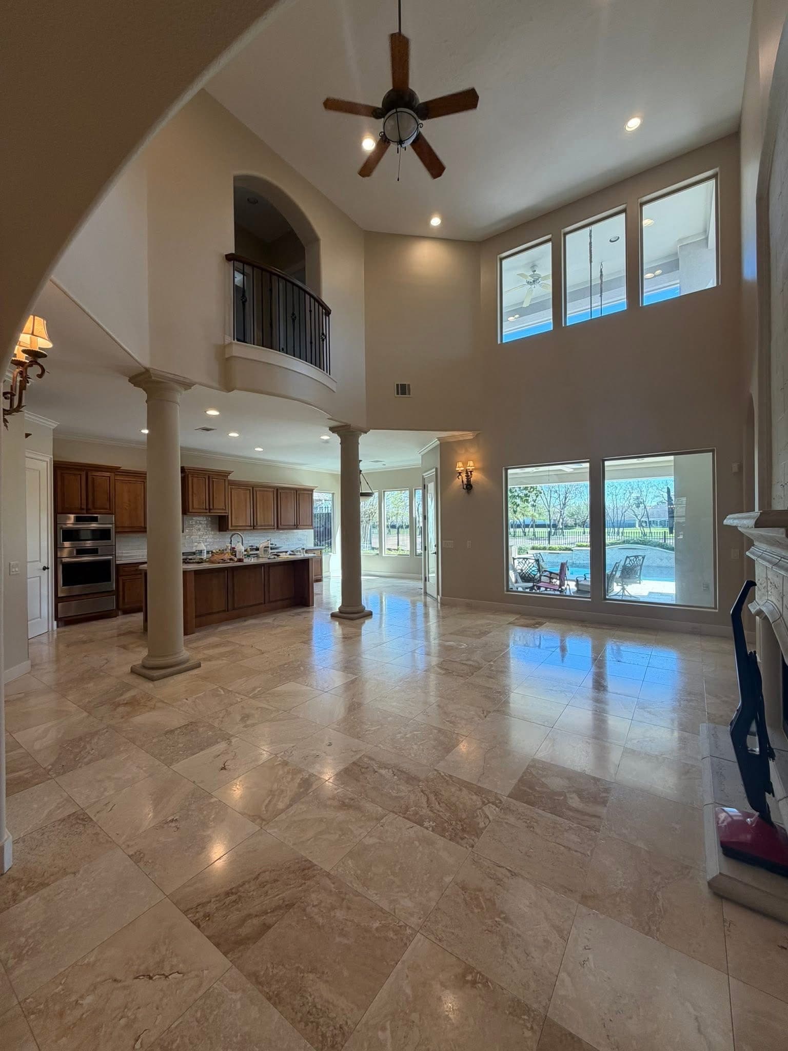 Polished travertine tile flooring in two-story luxury living room with pool view โ 2M Construction Huntsville AL